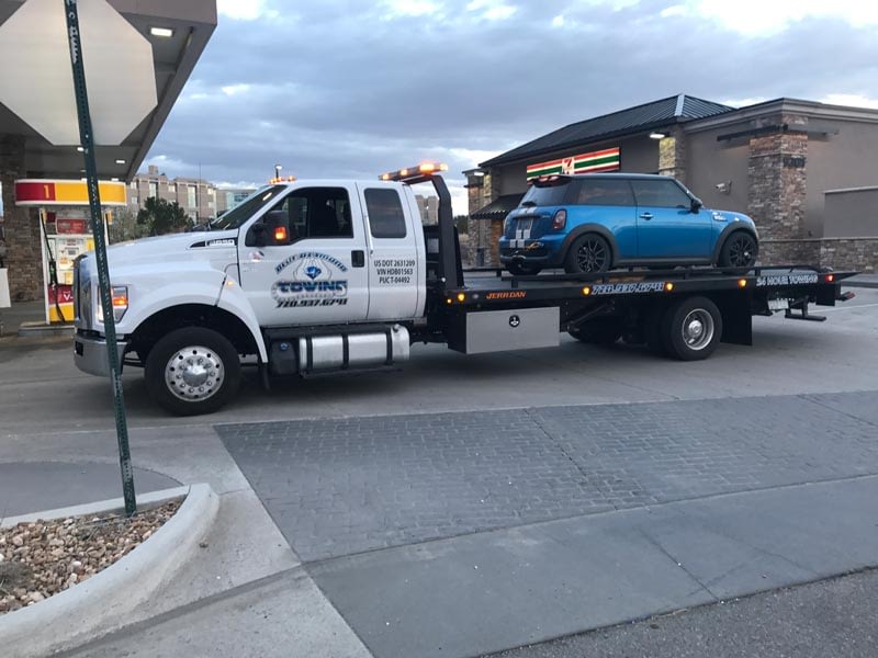 mini cooper being towed by flat bed tow truck after fuel problems